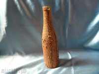 an old glass bottle decorated with the bark of a coniferous tree