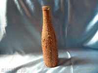 an old glass bottle decorated with the bark of a coniferous tree