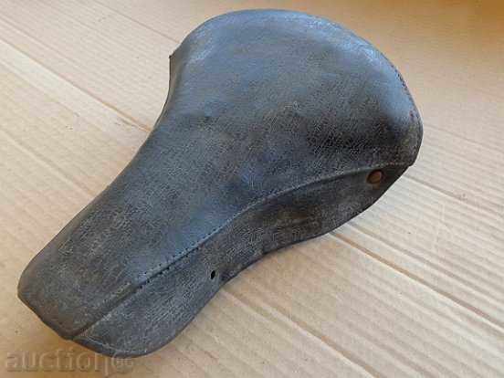 Old leather seat for bicycle, wheel