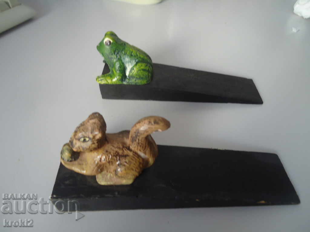 Two cast iron door stoppers on a wooden frog base