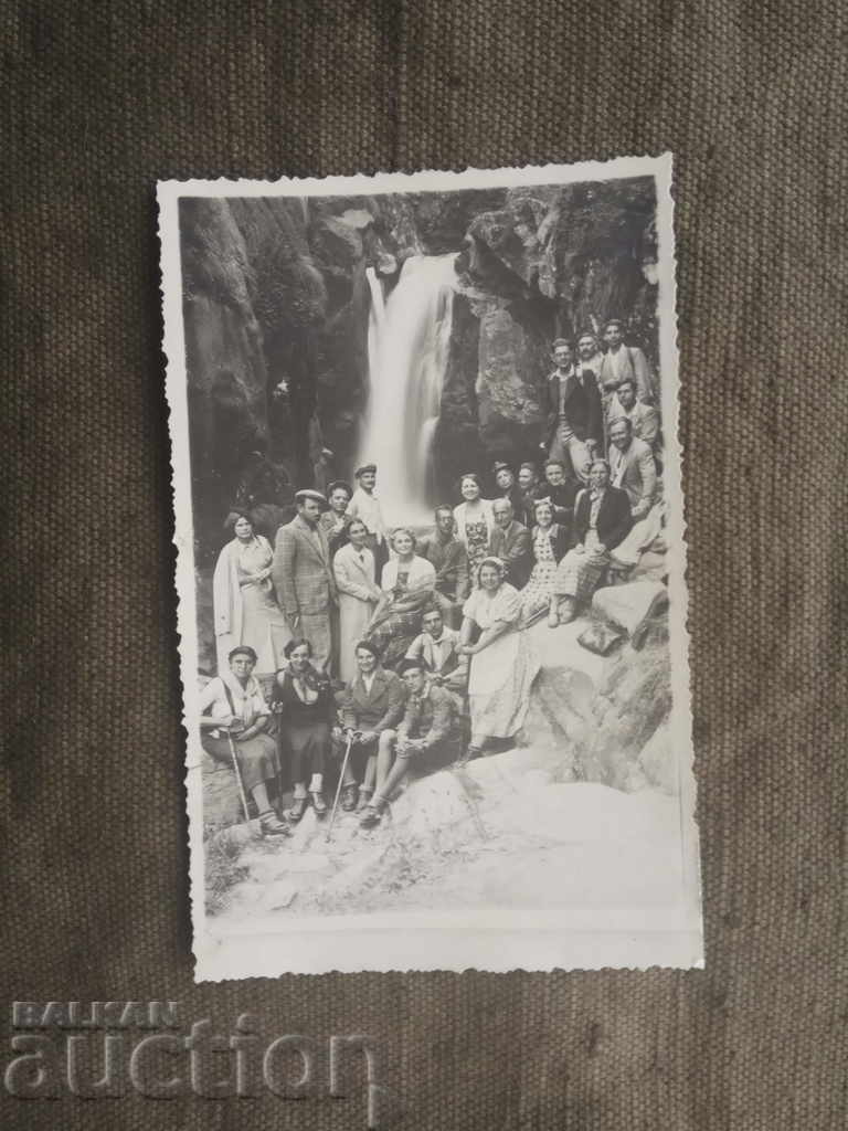 Turiști în fața unei cascade