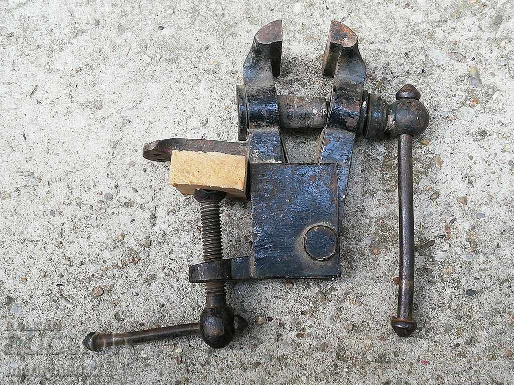 An old vise clamps a hardware tool