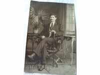 An old photo of a man with a cane is sitting
