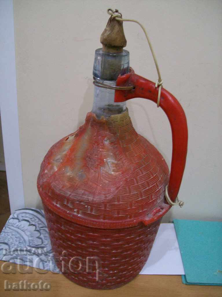 O sticlă damajana veche de 3 litri cu o împletitură de fagure deteriorată