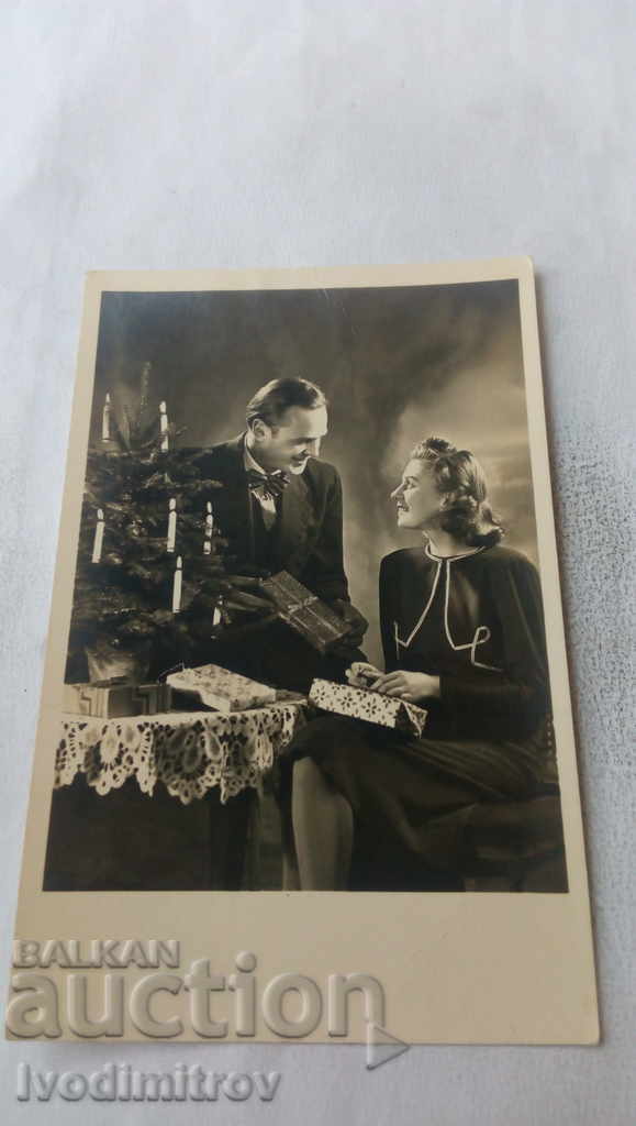 Postcard A man and a woman open New Year's presents