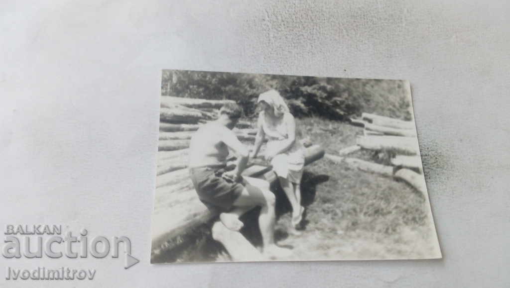Photo A man and a woman sitting on the logs
