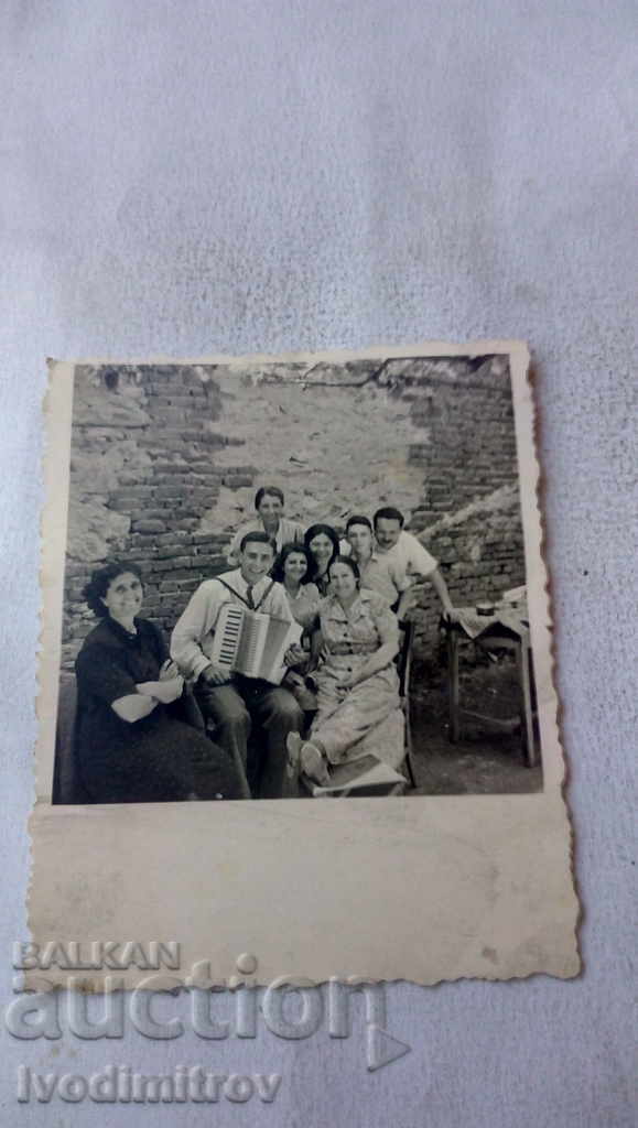 Photo A man with an accordion in the company of several women