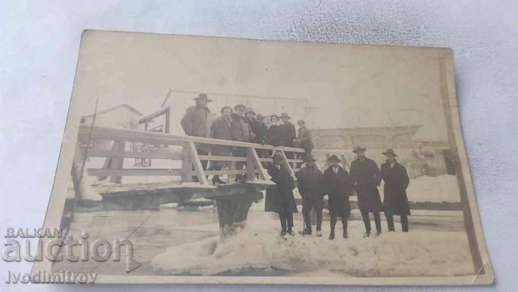 Photo Men and women on a wooden bridge over a river