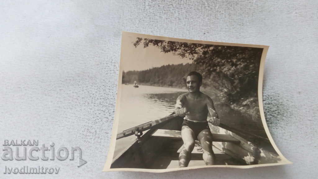 Fotografie Bărbat în costum de baie care vâslește o barcă în râu