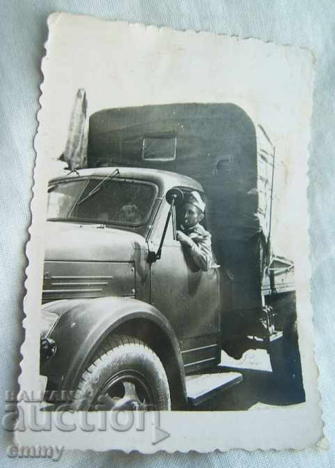 A small old photo of a soldier driving a ZIL military truck