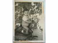 Mică fotografie veche a unui copil pe un leagăn de cal de lemn