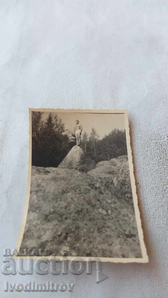 Foto Bărbat în pantaloni scurți pe o piatră