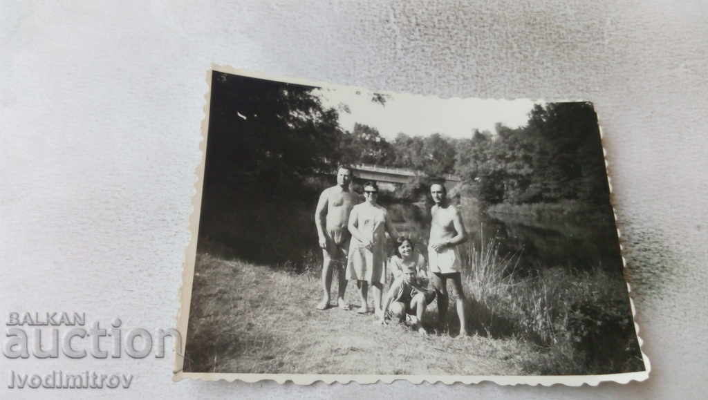 Photo Men in shorts and two women by the river