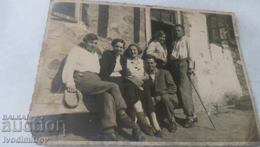 Photo Men and women on a wooden bench in front of a house