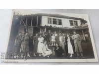 Φωτογραφία Άνδρες γυναίκες και παιδιά μπροστά από ένα παλιό εξοχικό σπίτι
