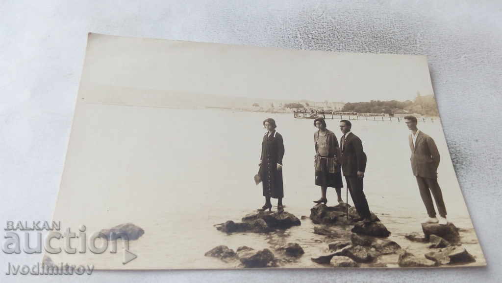 Photo Two men and two women on stones in the sea