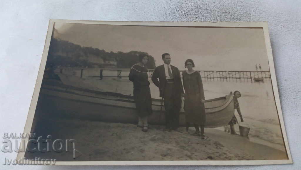 Photo of a man and two young girls in front of a boat on the shore