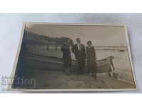 Photo of a man and two young girls in front of a boat on the shore