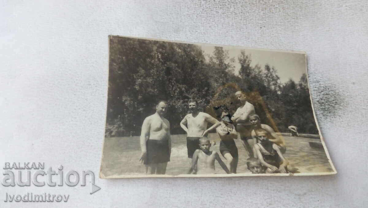 Foto Trei bărbați, femei și copii în costume de baie la piscină
