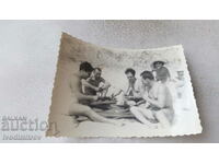 Photo Four men in swimsuits playing Bridge Belote on the beach