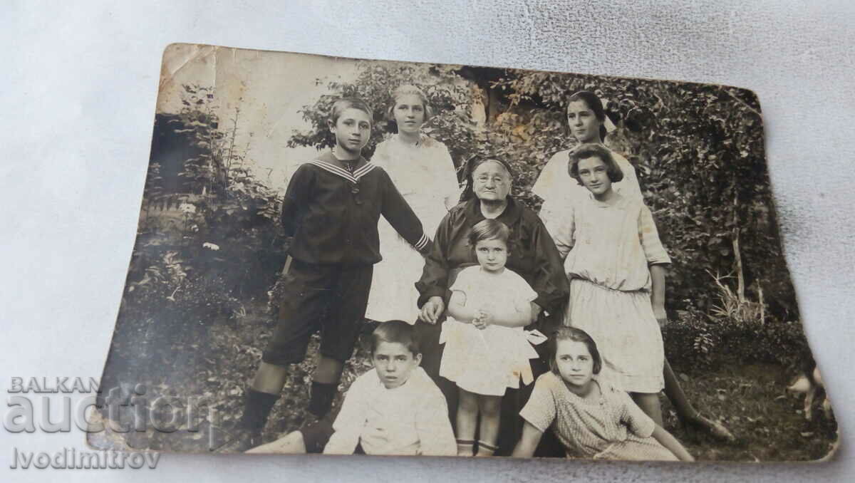 Fotografie O femeie în vârstă cu fete și băieți în curte