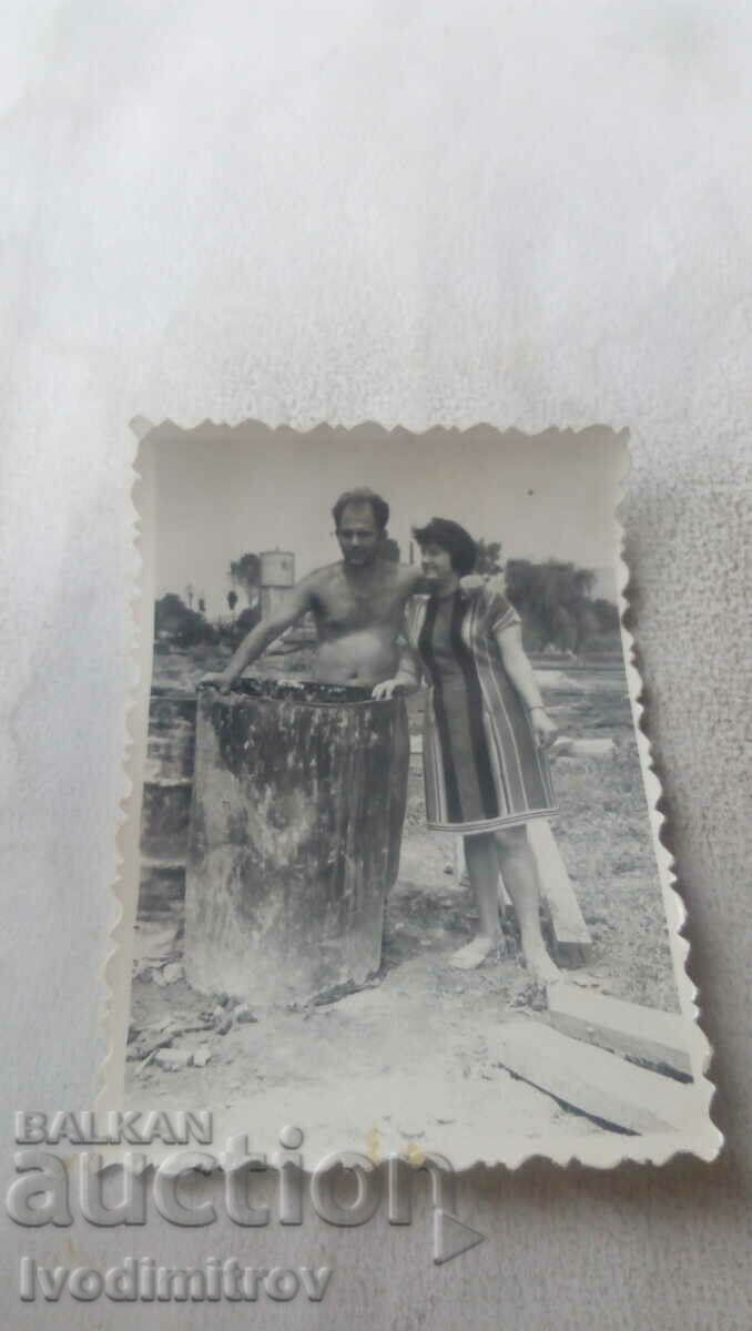 Photo Man and woman next to a barrel on a new building