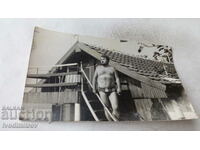 Fotografie cu un bărbat în costum de baie în fața unui bungalou
