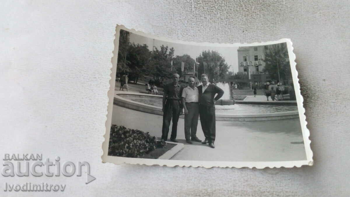 Φωτογραφία Τρεις άνδρες μπροστά από ένα σιντριβάνι