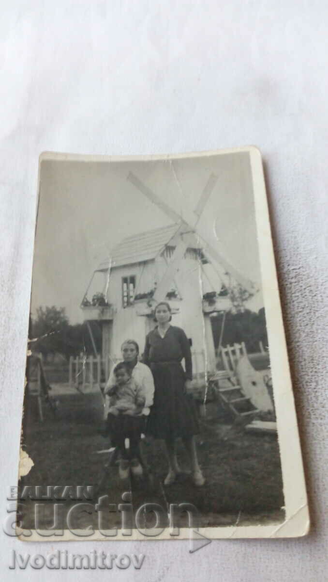 Fotografie Două femei și un băiat în fața unei mori de vânt