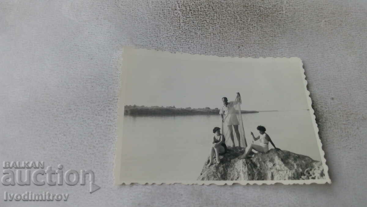 Fotografie cu un bărbat și două femei într-un costum de baie retro pe stâncă