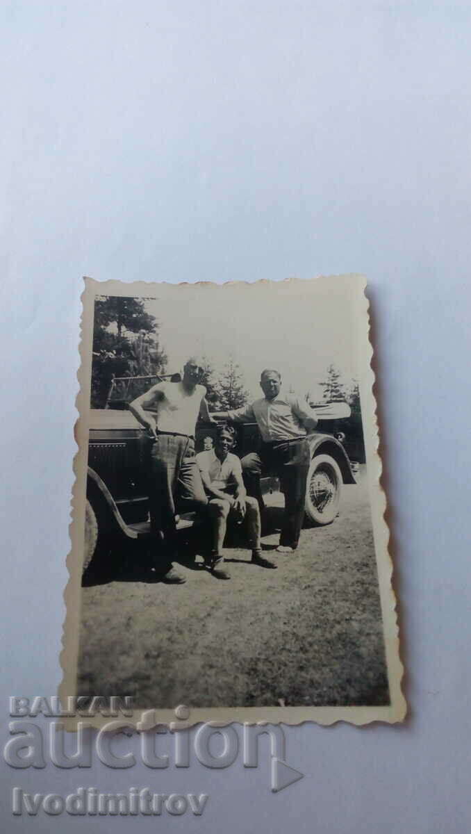 Foto Trei bărbați în fața unei mașini retro