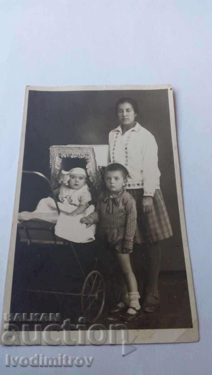 Φωτογραφία Γυναίκα με ένα μικρό αγόρι και ένα κορίτσι σε ένα καρότσι