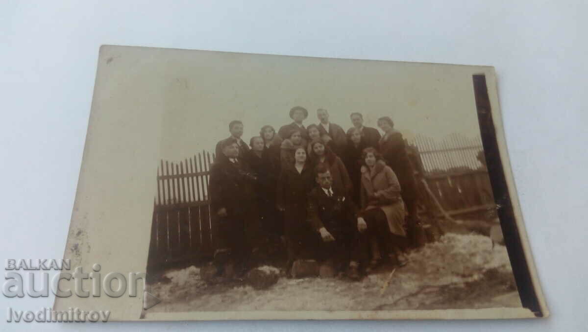 Photo Men and women next to a wooden fence