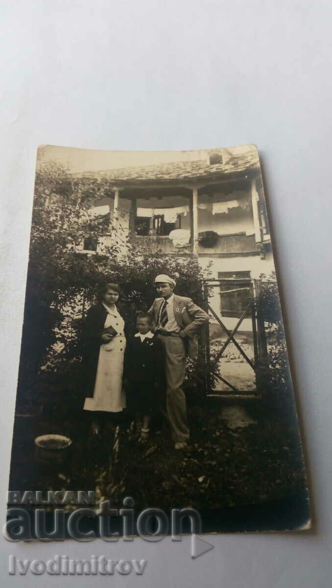 Снимка Мъж жена и момче пред къща с керемиди от тикли