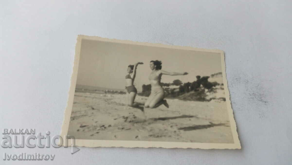 Photo Two young women jumping on the beach