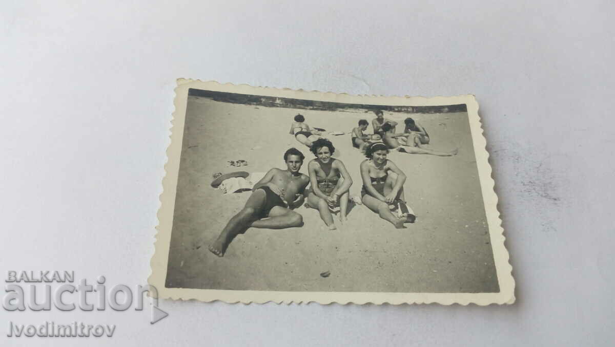 Fotografie cu un bărbat și două femei pe plajă