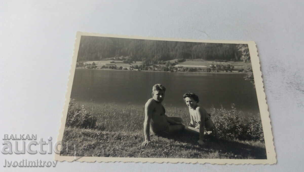 Fotografie cu un bărbat gol până la talie și o femeie pe malul unui lac