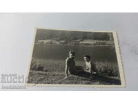 Photo of a man naked to the waist and a woman on the shore of a lake
