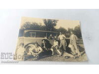 Photo Men, women and a boy with a vintage car on an outing