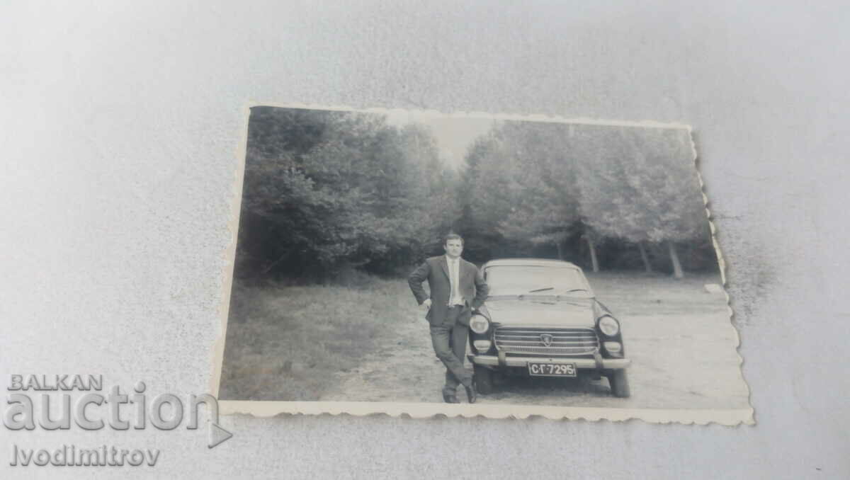 Photo A man next to a vintage PEUGEOT car