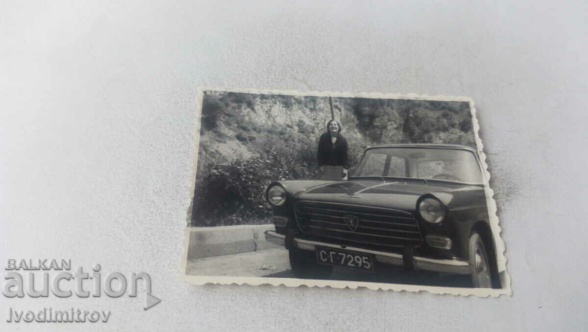 Photo Woman next to a vintage PEUGEOT car