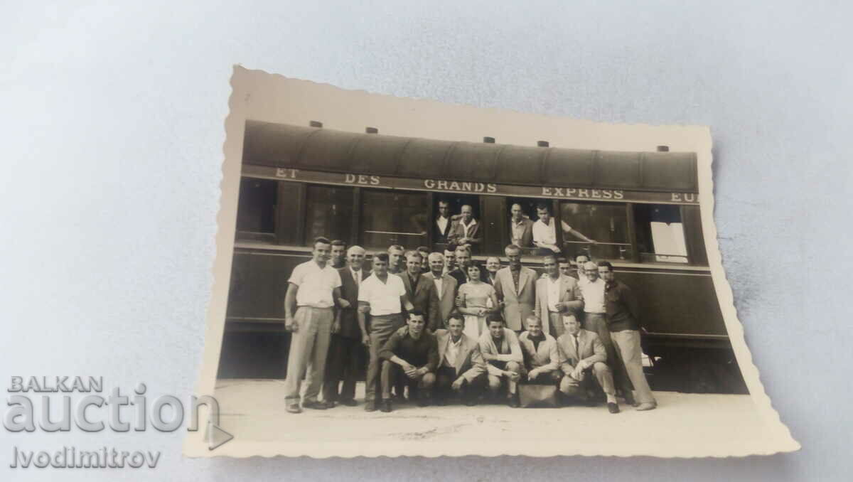 Fotografie Bărbați și femei în fața unui vagon de cale ferată