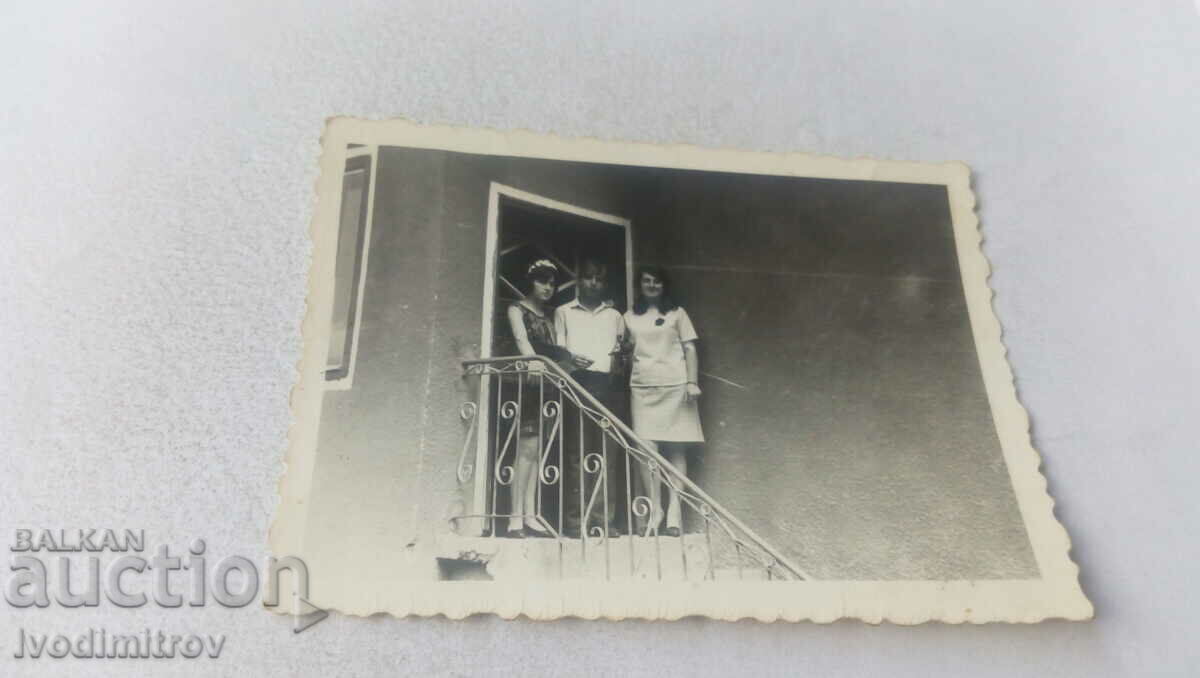 Photo A young man and two girls at the entrance to their home