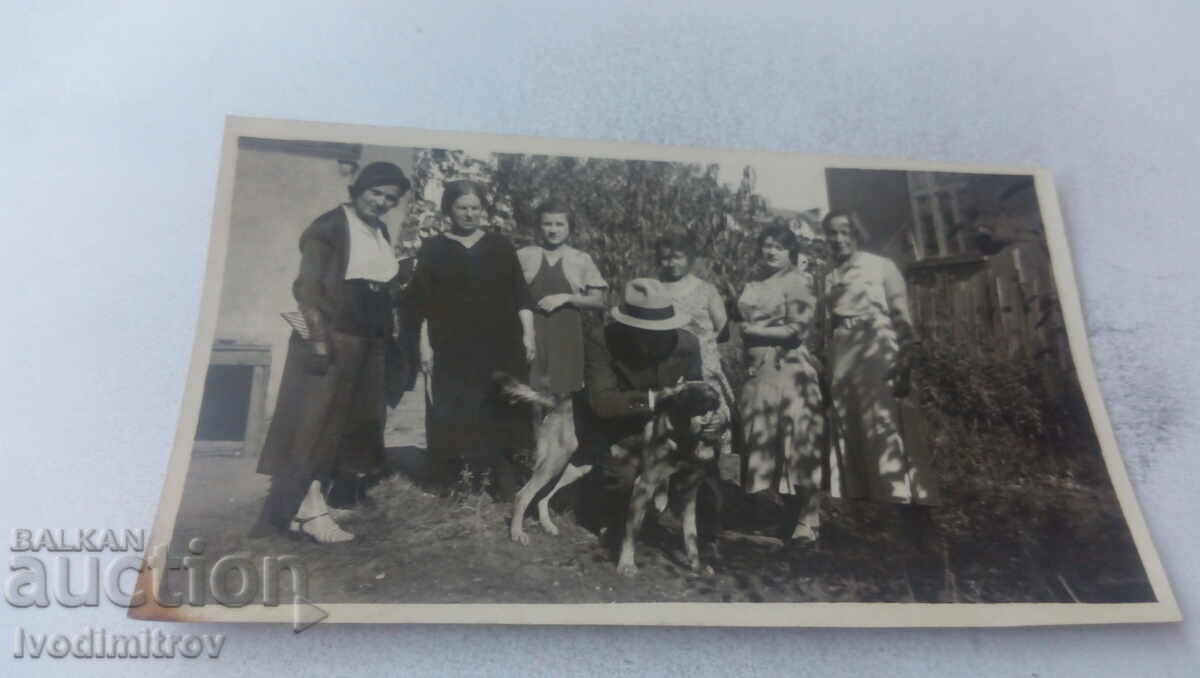 Foto Bărbați, femei și un câine în curtea casei lor