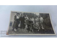 Photo Men, women and a dog in the yard of their house