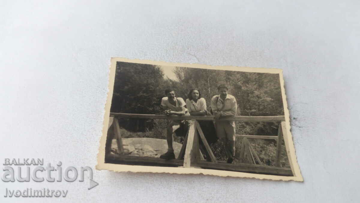 Photo Two young men and a girl on a wooden bridge