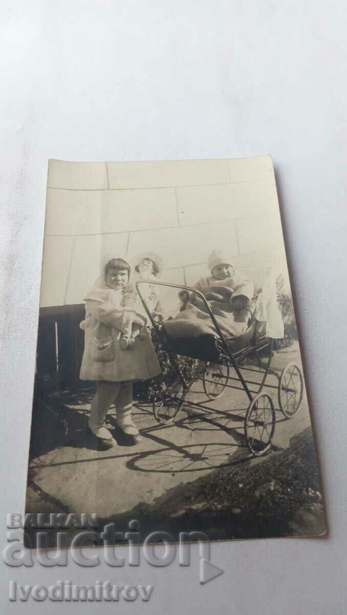 Φωτογραφία Το κοριτσάκι με μια κούκλα είναι ένα μωρό σε ένα vintage καρότσι