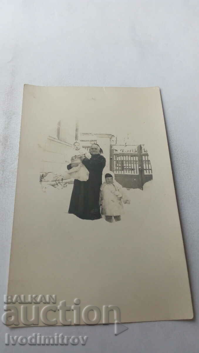Fotografie O fetiță și o femeie cu un copil în brațe iarna