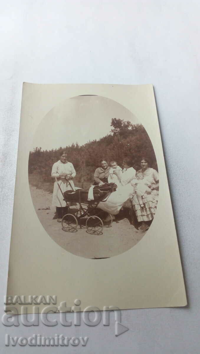 Photo Women and small children with a vintage baby carriage in the park