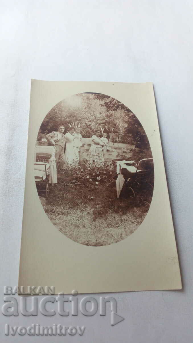 Fotografie Bărbați femei și doi bebeluși cu cărucioare de epocă în parc